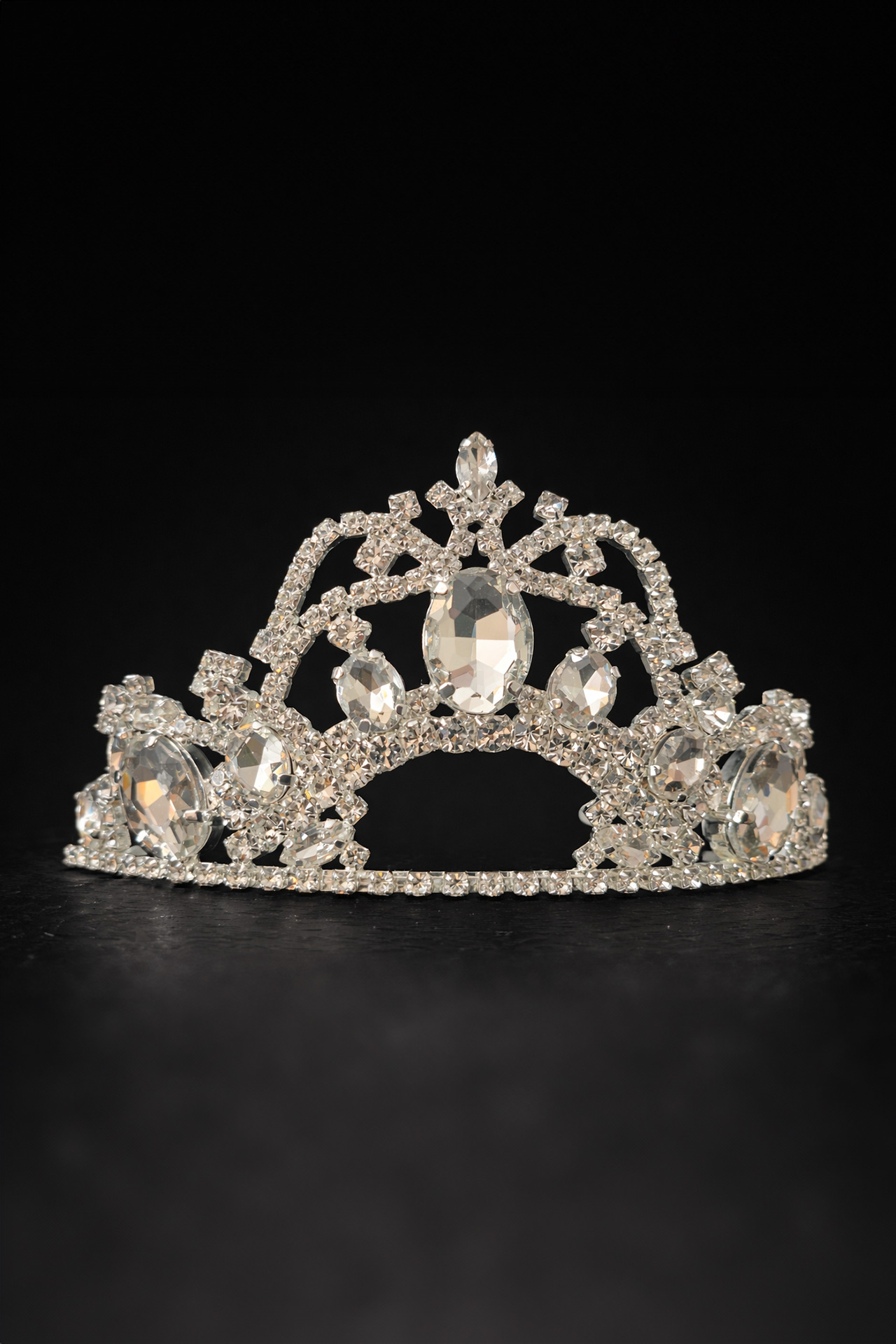 Silver crown tiara featuring a large central crystal surrounded by symmetrical patterns of smaller clear rhinestones.