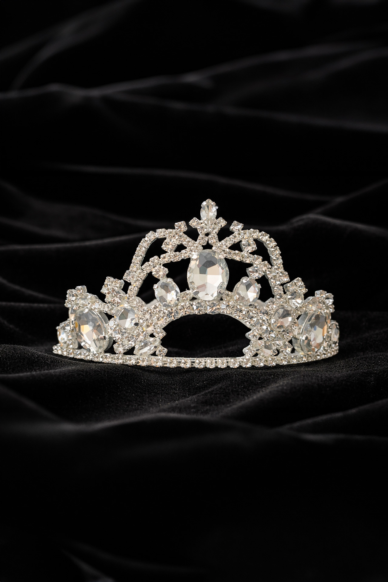 Silver crown tiara featuring a large central crystal surrounded by symmetrical patterns of smaller clear rhinestones.