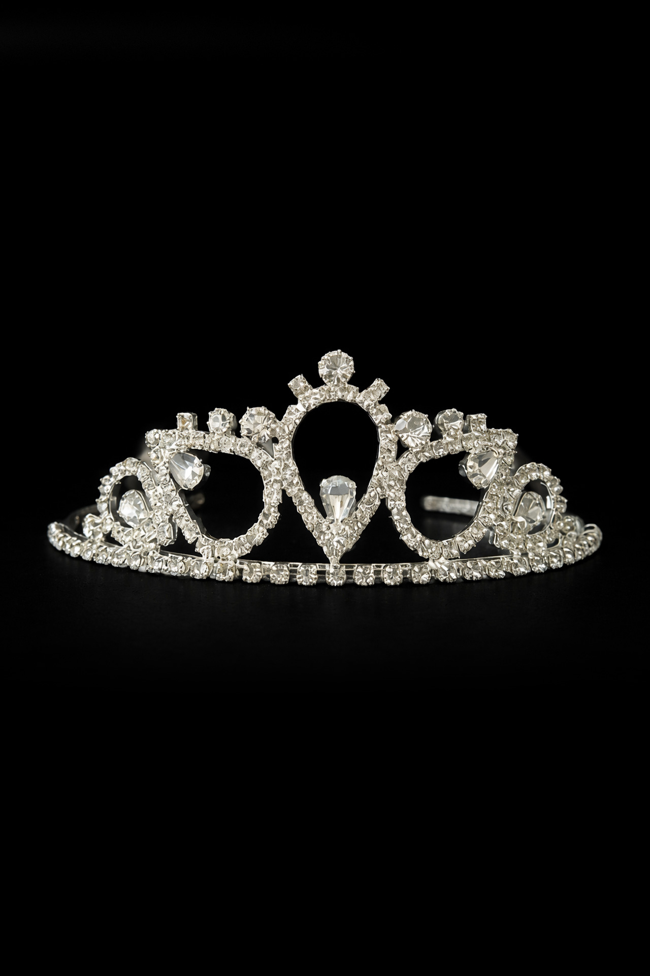 Silver tiara with a clear crystals and a prominent central stone set in a polished metal frame.
