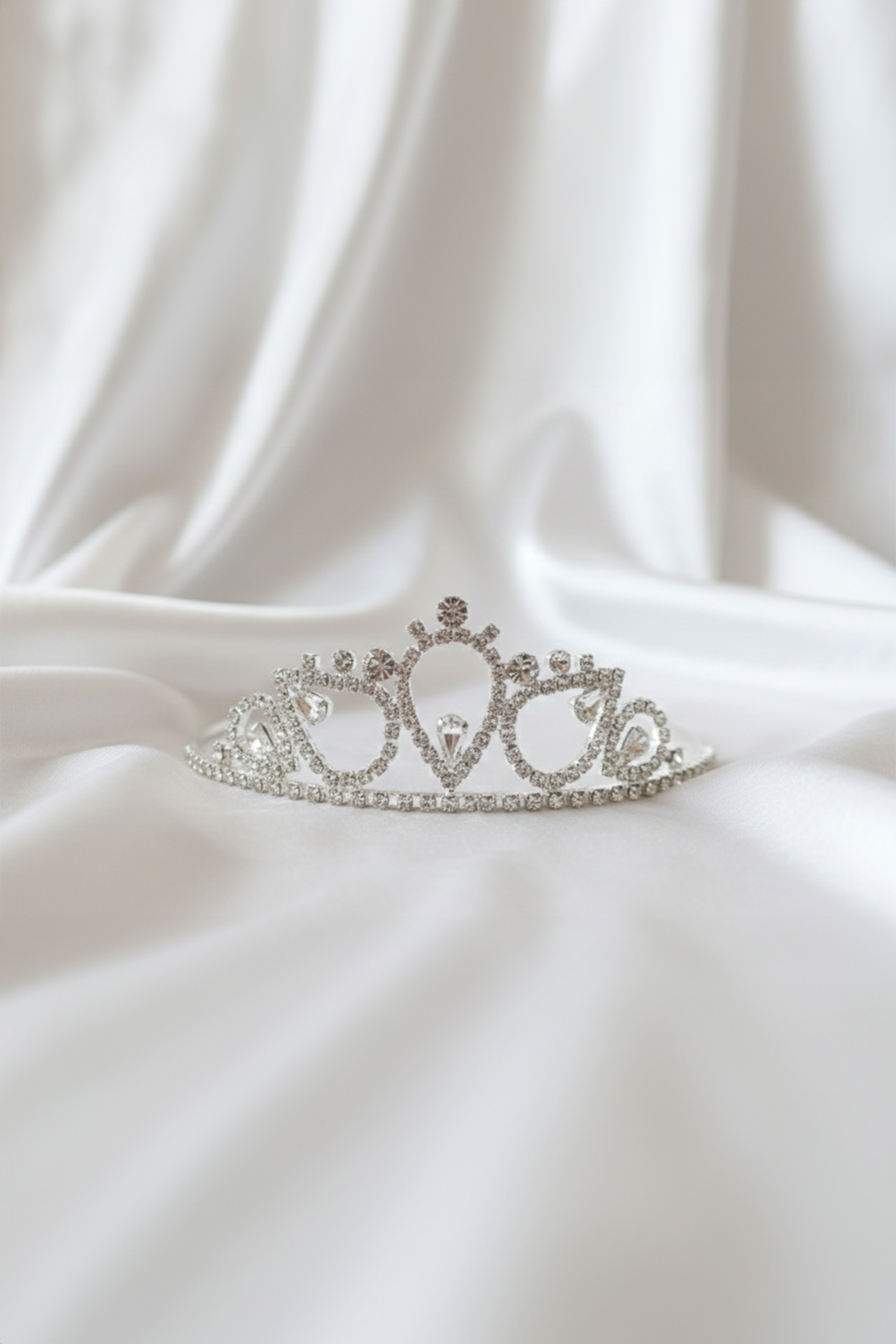 Silver tiara with a clear crystals and a prominent central stone set in a polished metal frame.