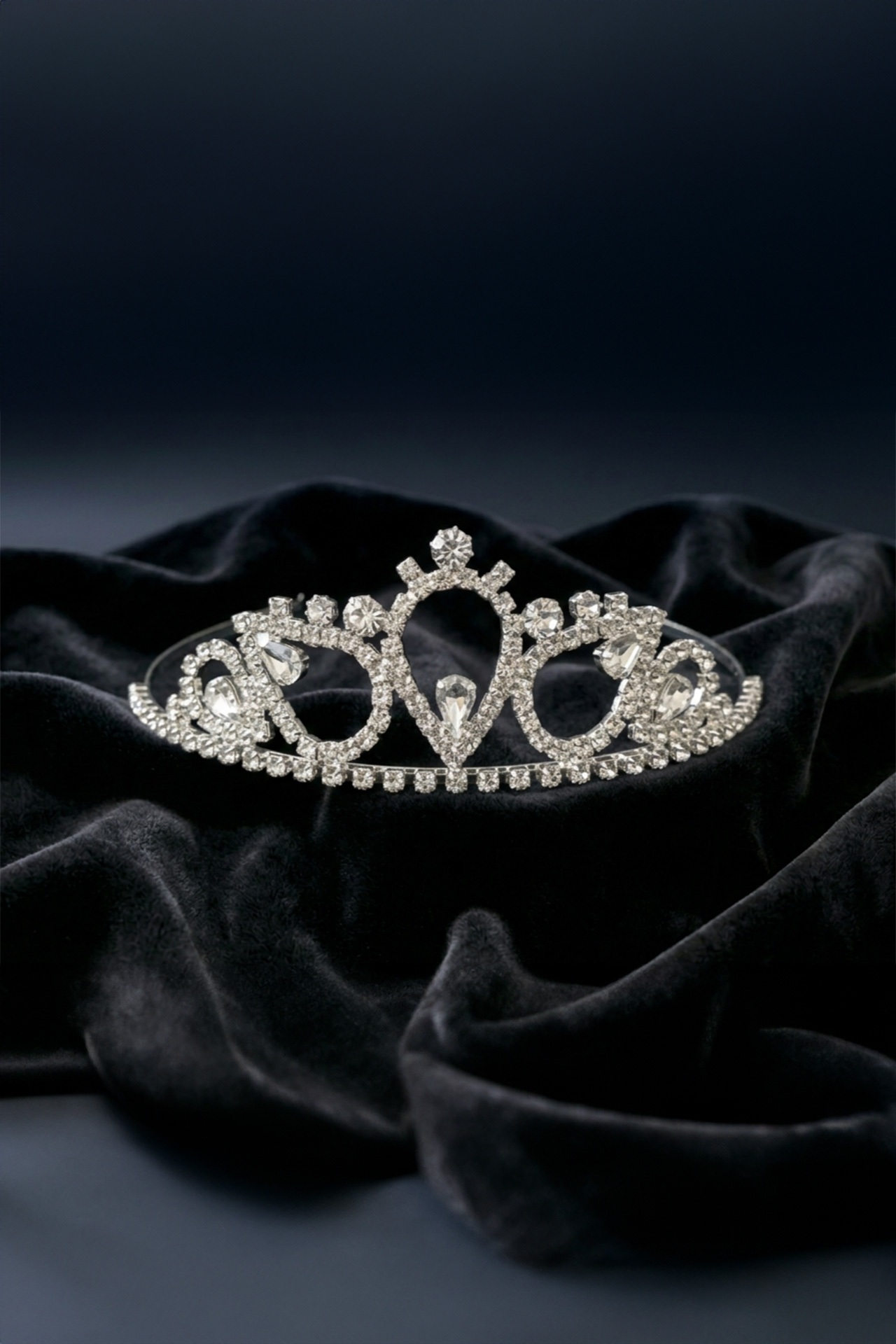 Silver tiara with a clear crystals and a prominent central stone set in a polished metal frame.