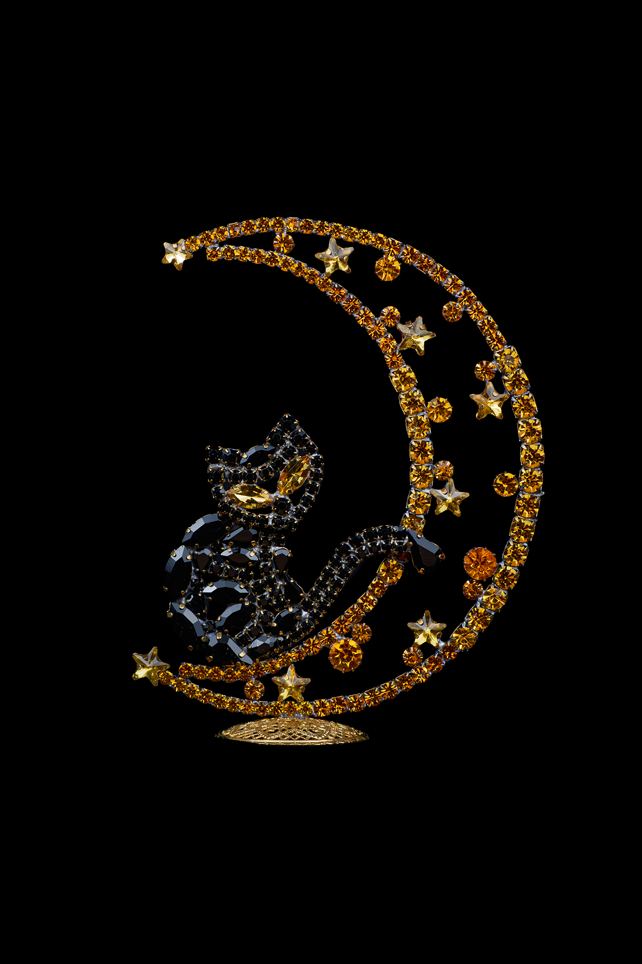 Rhinestone cat sitting on a crescent moon.
