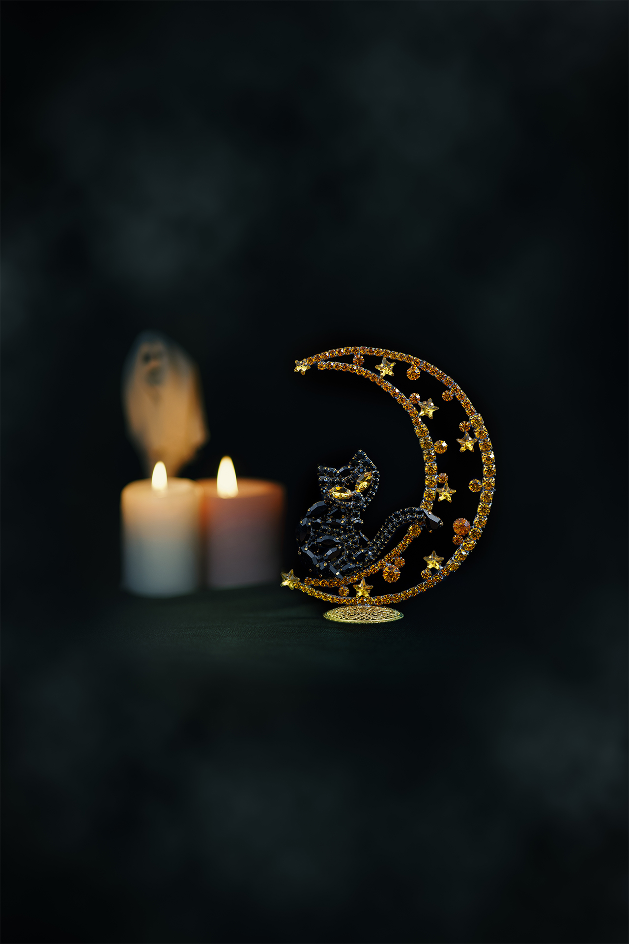 Rhinestone cat sitting on a crescent moon.