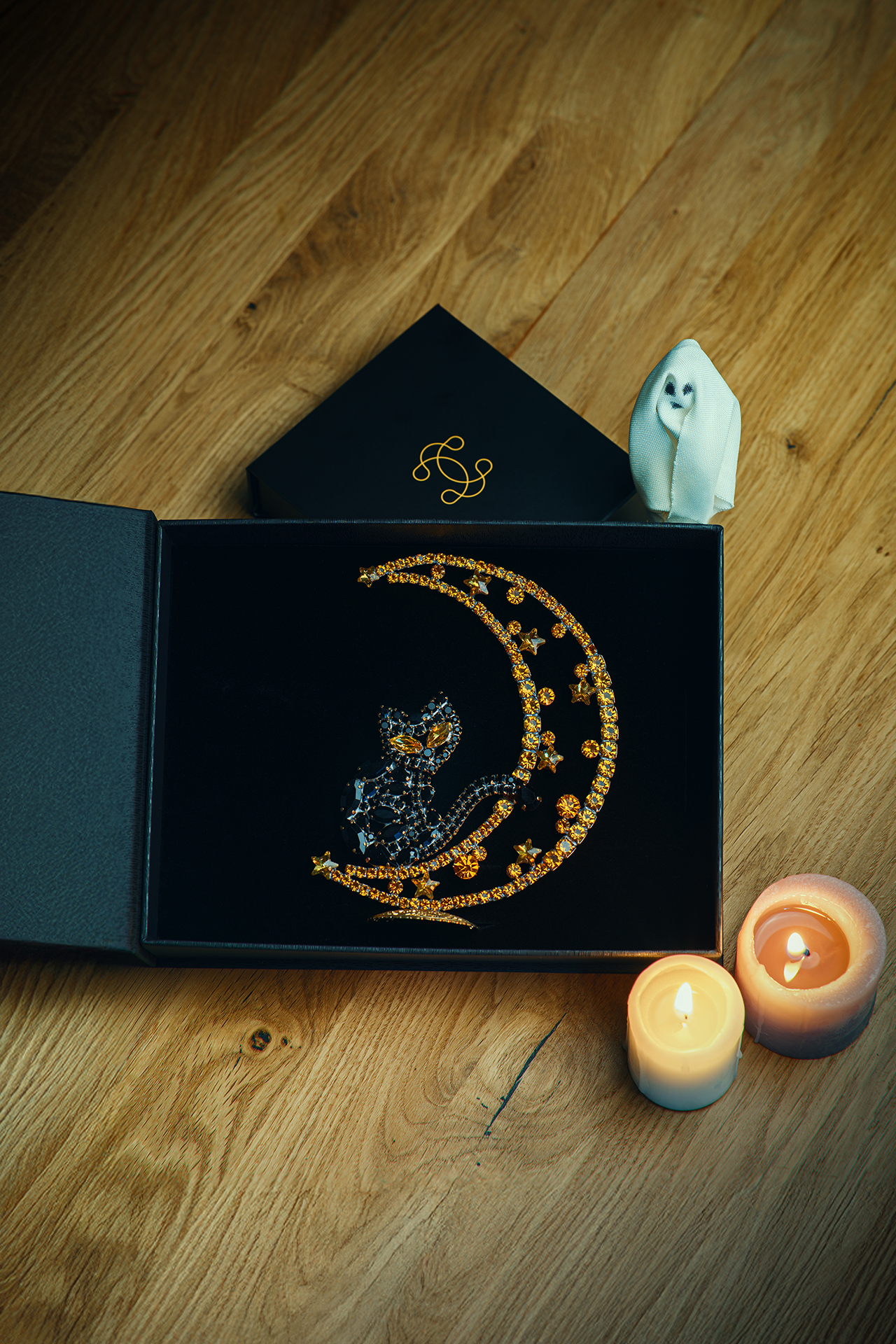 Rhinestone cat sitting on a crescent moon.