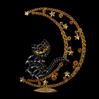 Rhinestone cat sitting on a crescent moon.